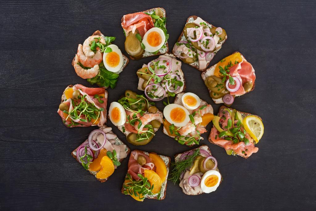 flache Lage mit dänischen Smorrebrod-Sandwiches mit Pfirsichkonserven und Eiern auf grauer Oberfläche  - Foto, Bild