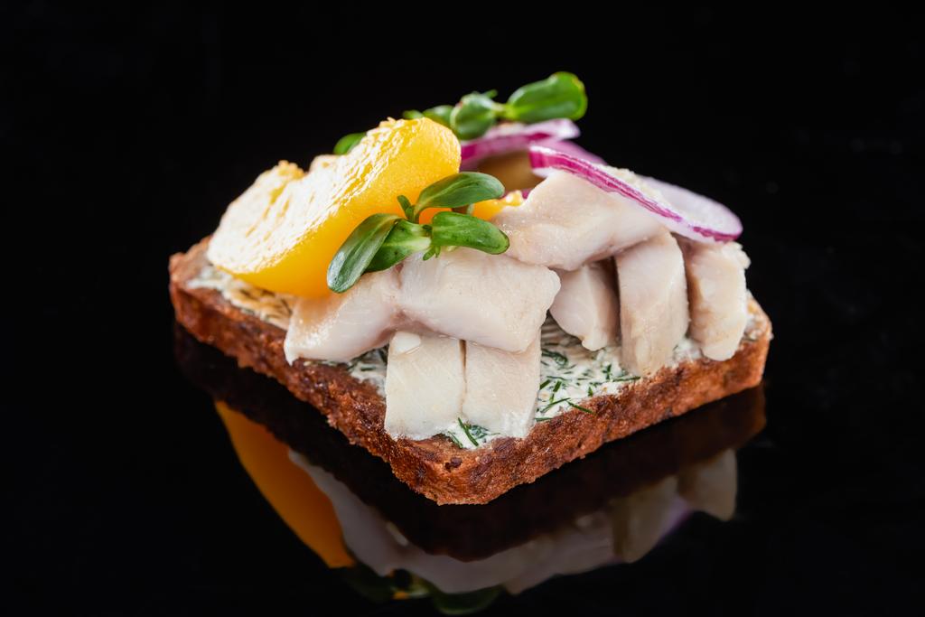 κλείσιμο των ψαριών ρέγγας σε νόστιμο σάντουιτς smorrebrod σε μαύρο  - Φωτογραφία, εικόνα