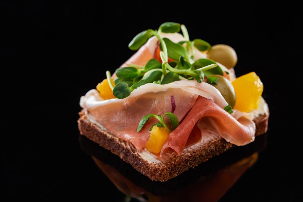 Nahaufnahme von Schinken auf zubereitetem dänischen Smorrebrod-Sandwich auf Schwarz  - Foto, Bild