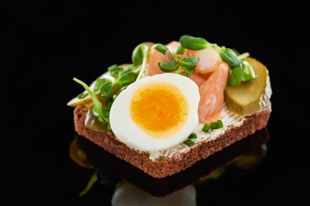 primer plano de huevo hervido cerca de salmón en smorrebrod sándwich danés en negro
  - Foto, imagen