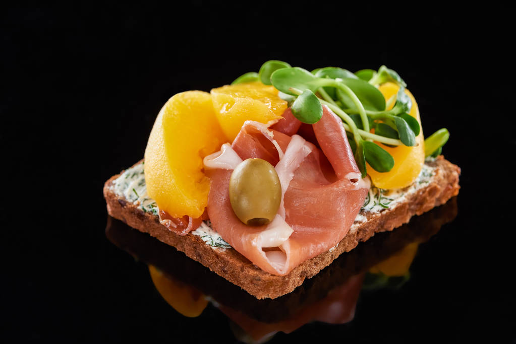 enfoque selectivo de jamón y duraznos enlatados en smorrebrod sándwich en negro
  - Foto, Imagen