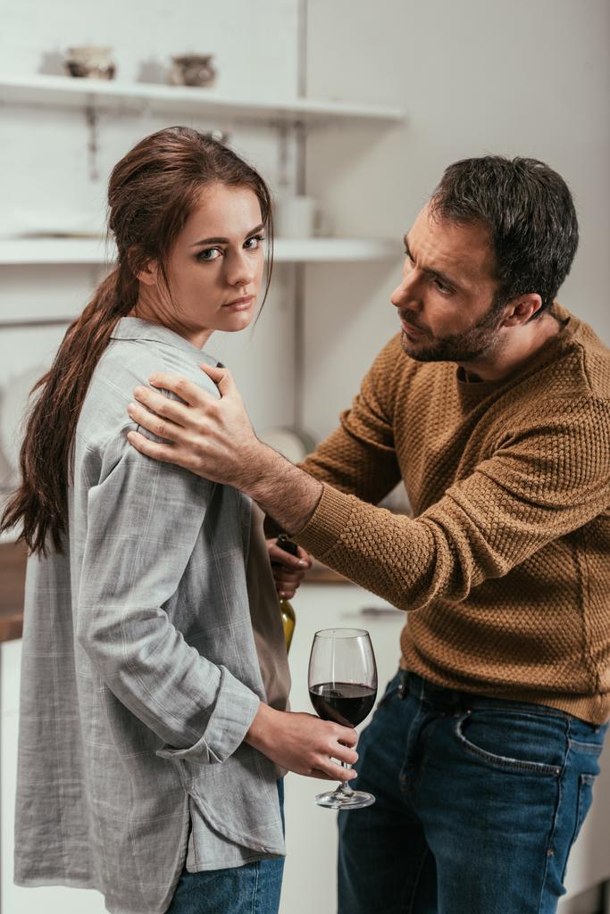 Egy férfi vitatkozik egy alkoholista feleséggel a konyhában. - Fotó, kép