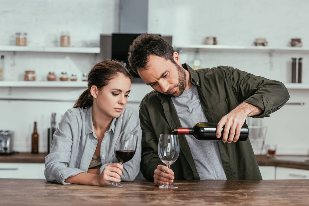 Alkoholfüggő pár vörösbort tölt a konyhára. - Fotó, kép