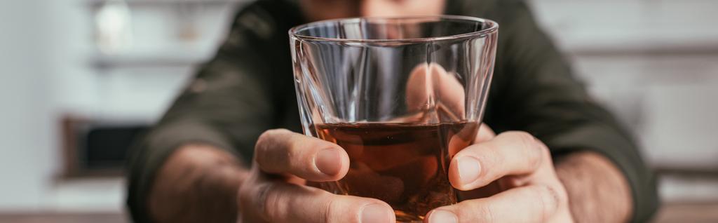 Selective focus of man holding whiskey glass in hands, panoramic shot - 写真・画像