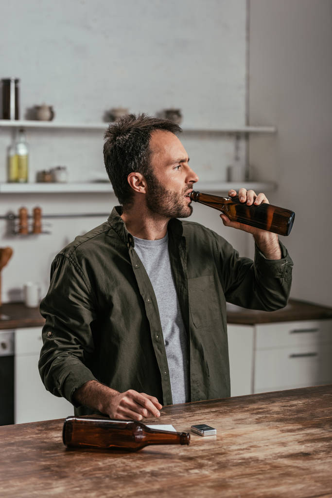Alkoholfüggő férfi sört iszik a konyhában. - Fotó, kép