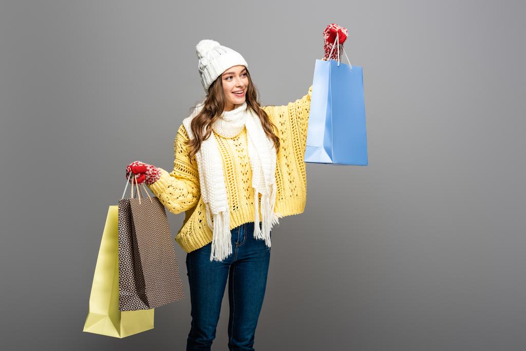 boldog nő téli ruhában bevásárló táskák szürke háttér - Fotó, kép