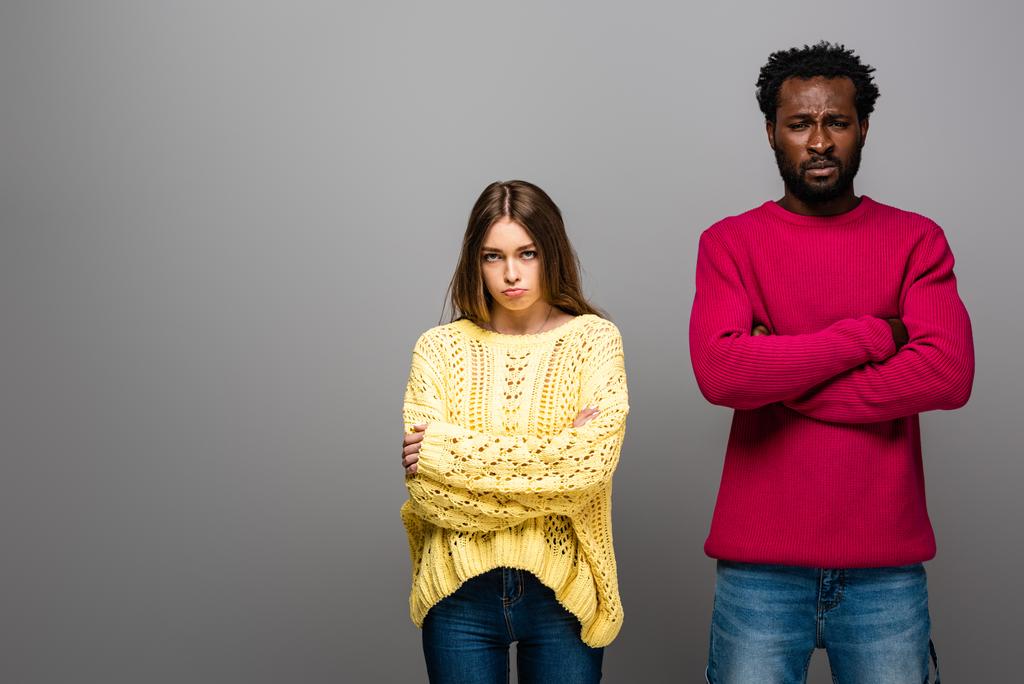 offended interracial couple in knitted sweaters on grey background - Photo, Image