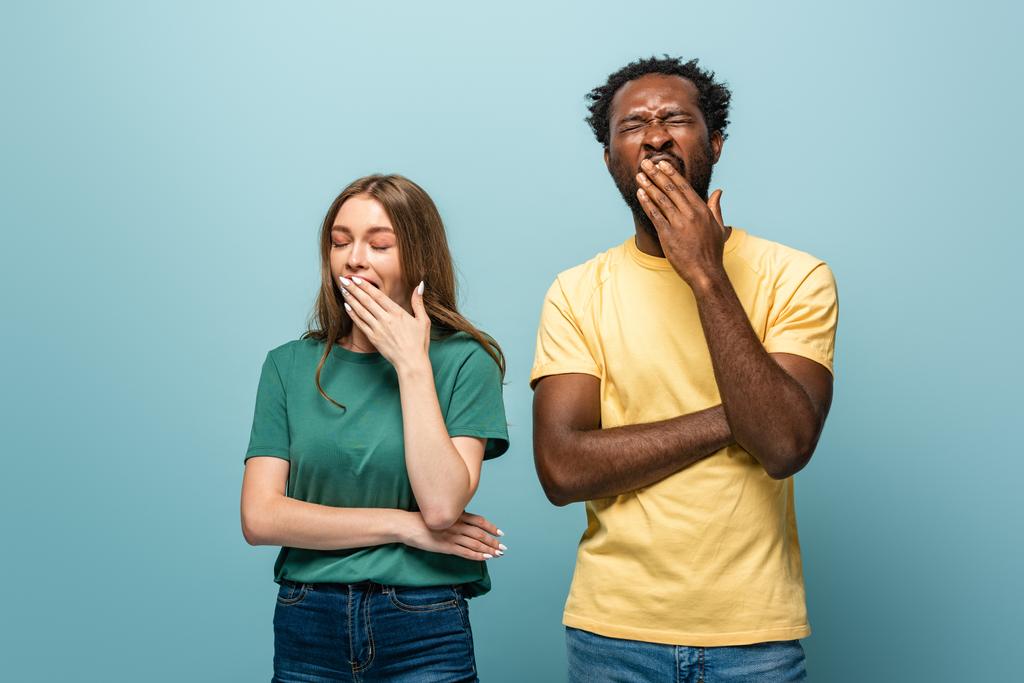 sleepy interracial couple yawning on blue background - Photo, Image
