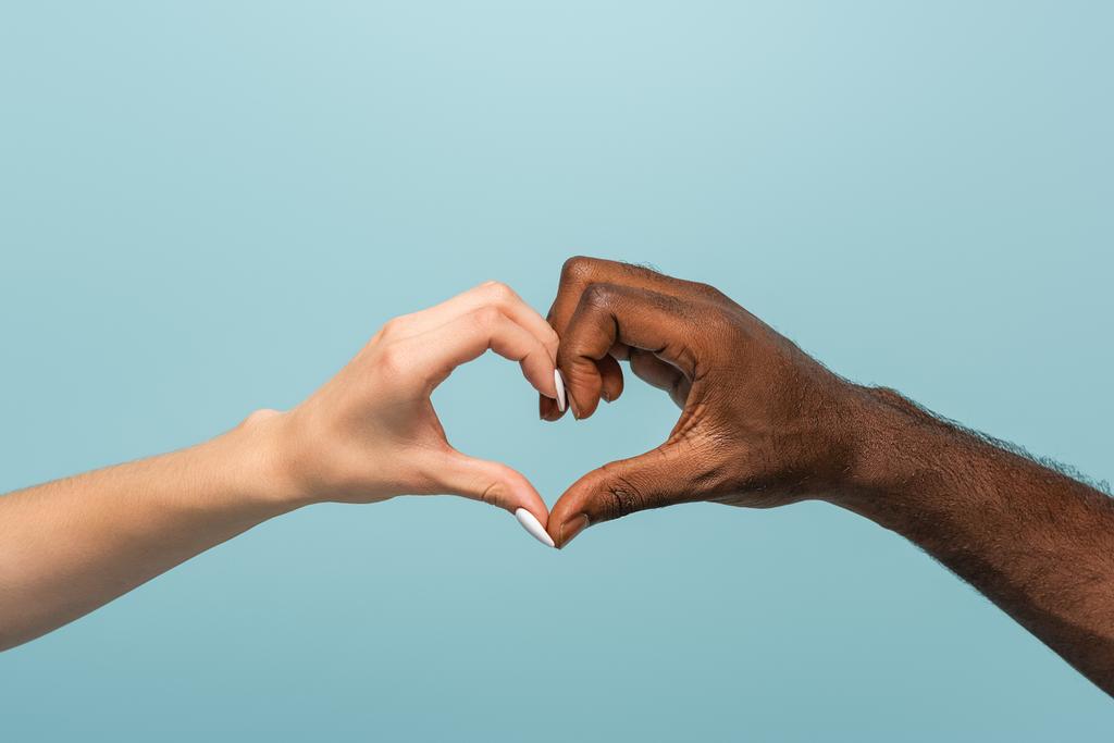vue recadrée du couple interracial montrant un geste cardiaque isolé sur bleu
 - Photo, image