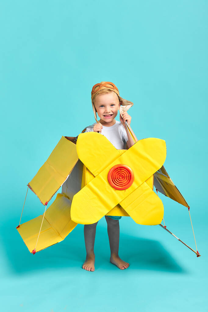 Alegre niño caucásico en traje de piloto y avión de juguete - Foto, Imagen