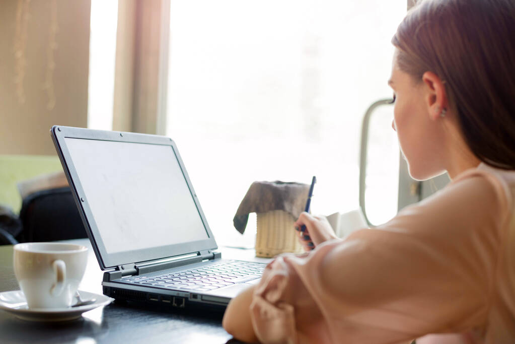 Piękna dziewczyna pracuje na laptopie przy stole w kawiarni - Zdjęcie, obraz