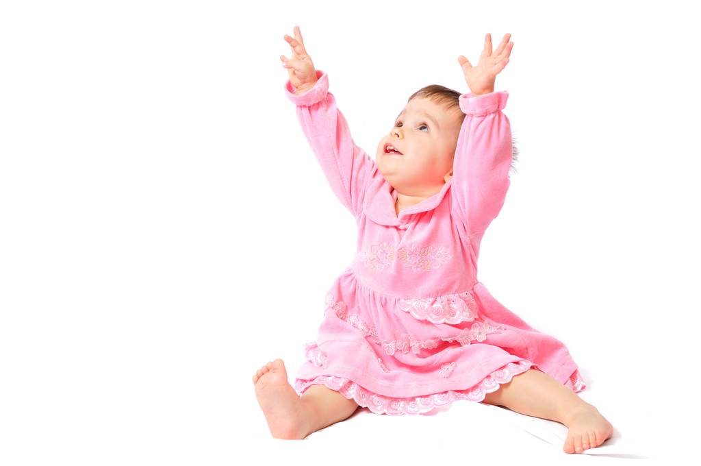Pembe elbiseli bebek elleri havada oturuyor. - Fotoğraf, Görsel
