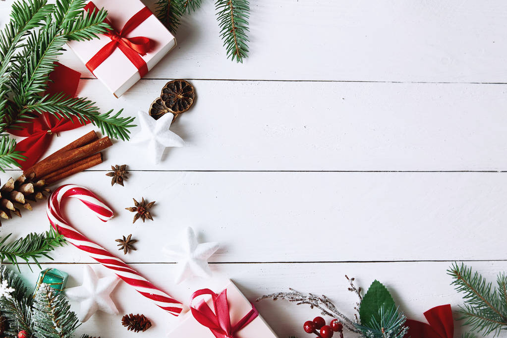 Prachtige kerstcompositie op witte achtergrond met kerstcadeaudozen, besneeuwde dennentakken, naaldbomen, vakantiedecoratie, karamelstokje en rode bes. Bovenaanzicht, kopieer ruimte. - Foto, afbeelding