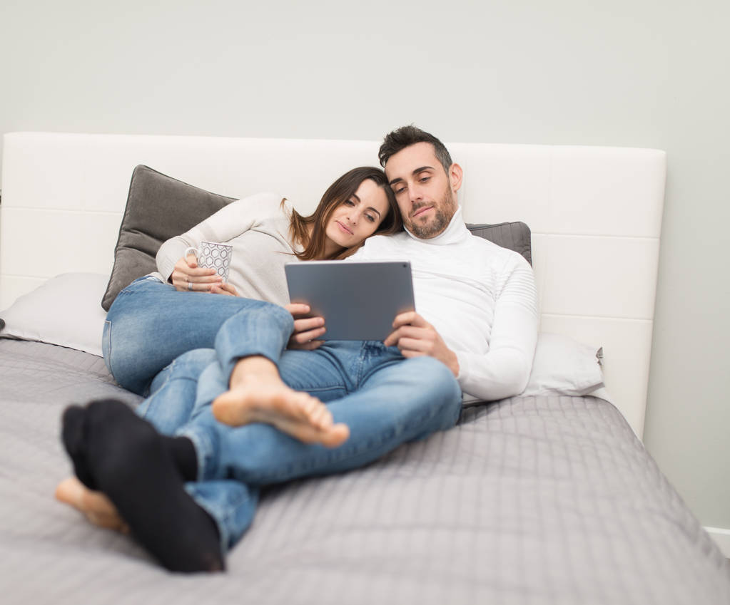 junges Paar schaut auf dem Bett einen Film auf dem Tablet - Foto, Bild