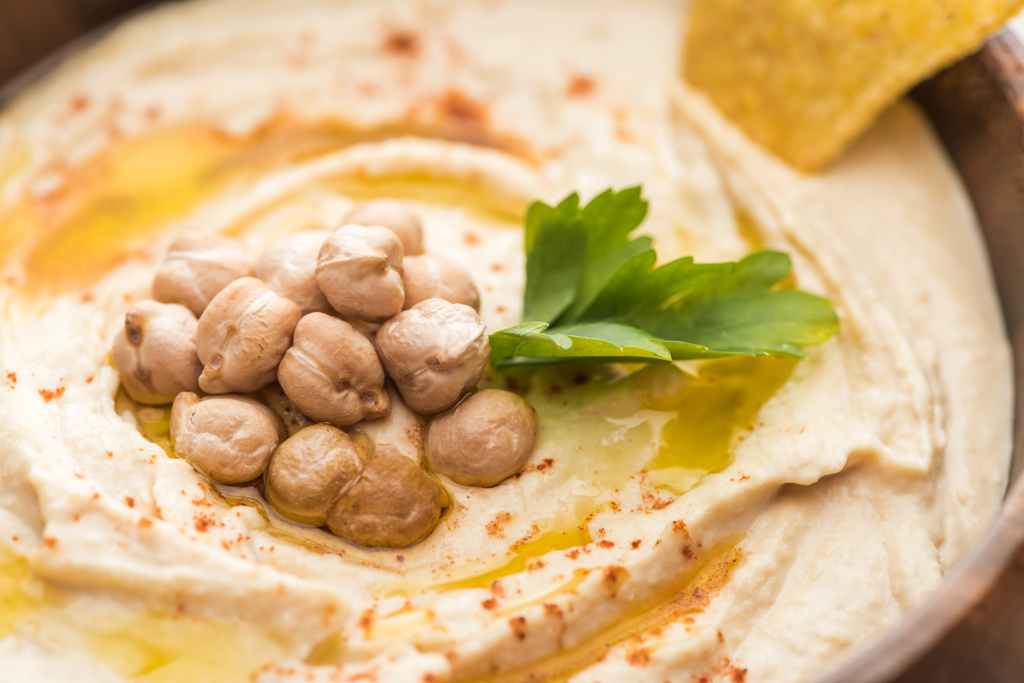 Nahaufnahme von köstlichem Hummus mit Kichererbsen und Nacho in Schüssel - Foto, Bild