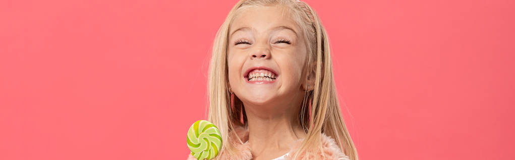 Gülümseme ve şeker çocuğun lolipop tutarken çekilen panoramik görüntüsü. Pembe üzerine izole edilmiş. - Fotoğraf, Görsel