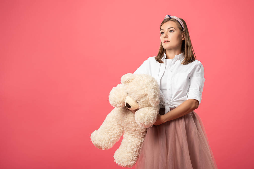 attractive and stylish woman holding teddy bear isolated on pink  - 写真・画像
