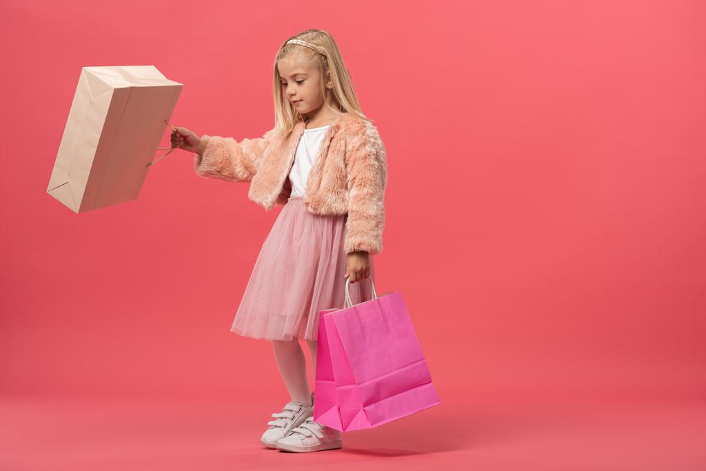 mignon enfant tenant des sacs à provisions sur fond rose avec espace de copie
  - Photo, image
