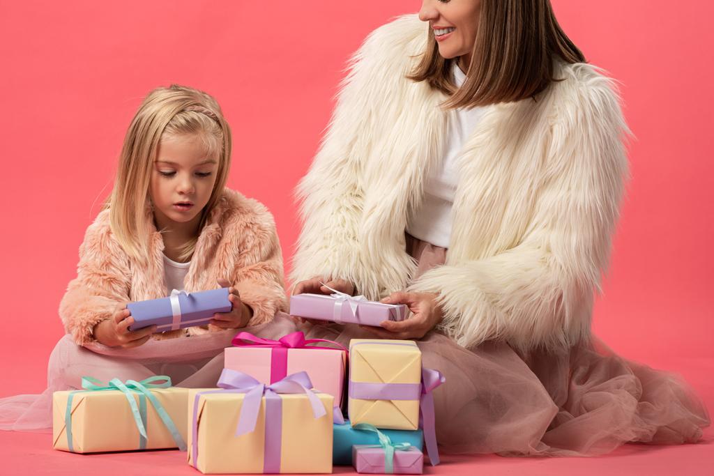 bijgesneden weergave van moeder en dochter met geschenken op roze achtergrond  - Foto, afbeelding