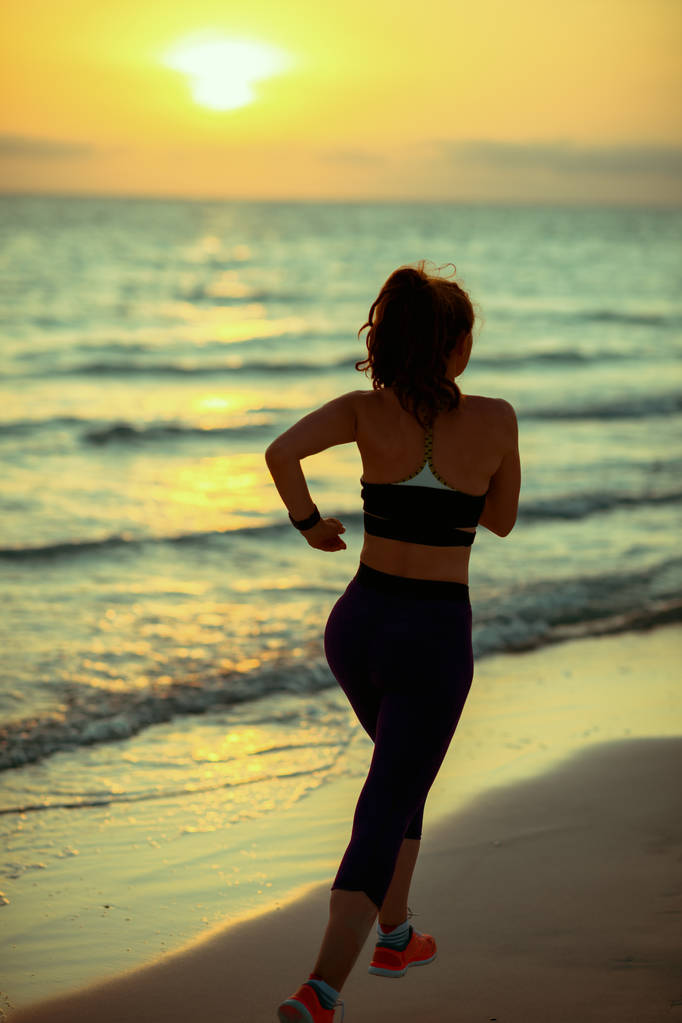 Silhouette de femme sportive en bonne santé dans des vêtements de style sportif sur le bord de mer dans la soirée en cours d'exécution
. - Photo, image