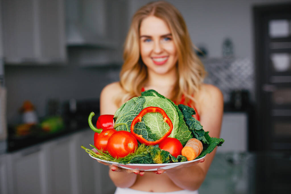 Sport fille dans une cuisine avec des légumes
 - Photo, image