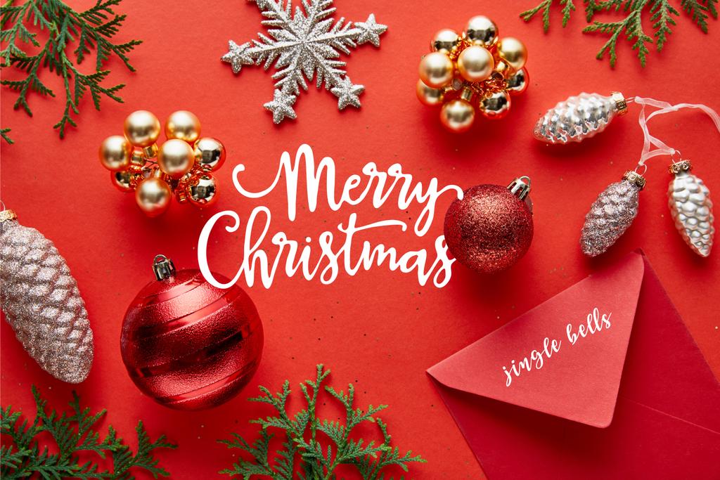 horní pohled na lesklé vánoční dekorace, obálka a thuja na červeném pozadí s veselým vánoční ilustrace - Fotografie, Obrázek