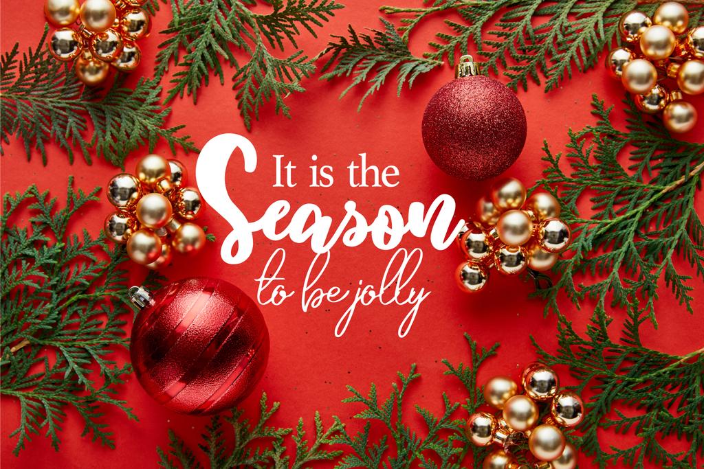 vista superior de la decoración brillante de Navidad y thuja sobre fondo rojo con él es la temporada para ser letras alegres
 - Foto, imagen