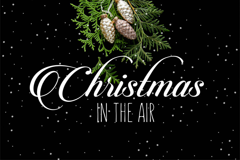 horní pohled na lesklé zlaté vánoční kornouty na zelené větve thuja izolované na černé s Vánocemi ve vzduchu ilustrace - Fotografie, Obrázek