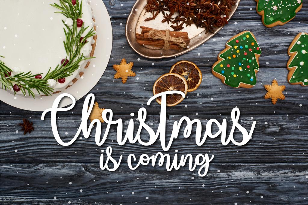 shora pohled na vánoční koláč, koření a sušenky na tmavém dřevěném stole s Vánocemi se blíží ilustrace - Fotografie, Obrázek