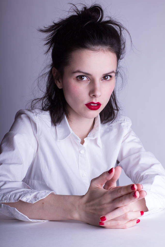 beautiful young girl in a white shirt on a white background with red lipstick on her lips - Photo, Image