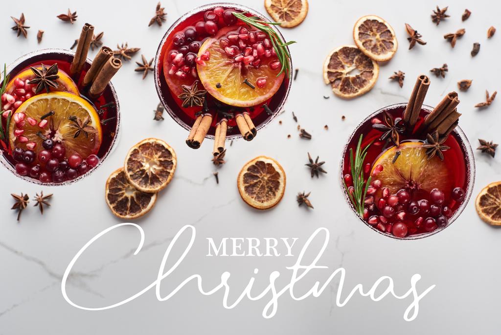 vista superior de coquetéis de Natal com laranja, romã, canela com feliz Natal ilustração
  - Foto, Imagem