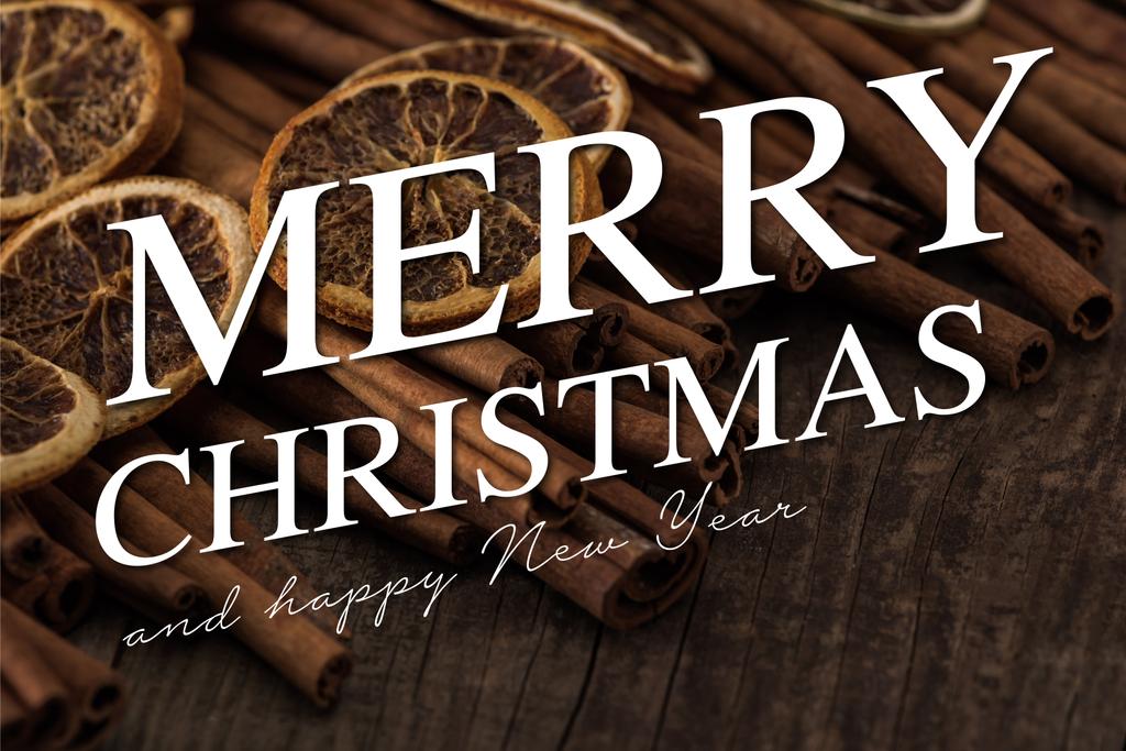 vista de perto de fatias de laranja secas e canela no fundo de madeira com Feliz Natal e feliz ilustração do ano novo
 - Foto, Imagem