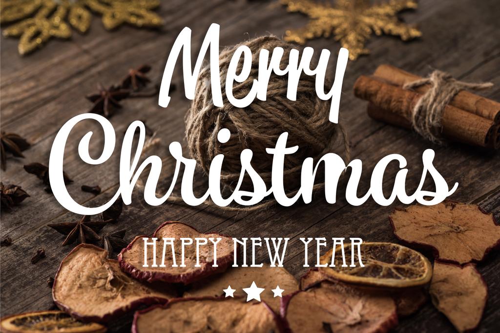 сушені цитрусові та яблучні скибочки біля кулі нитки на дерев'яній поверхні з веселим Різдвом та щасливою новорічною ілюстрацією
 - Фото, зображення