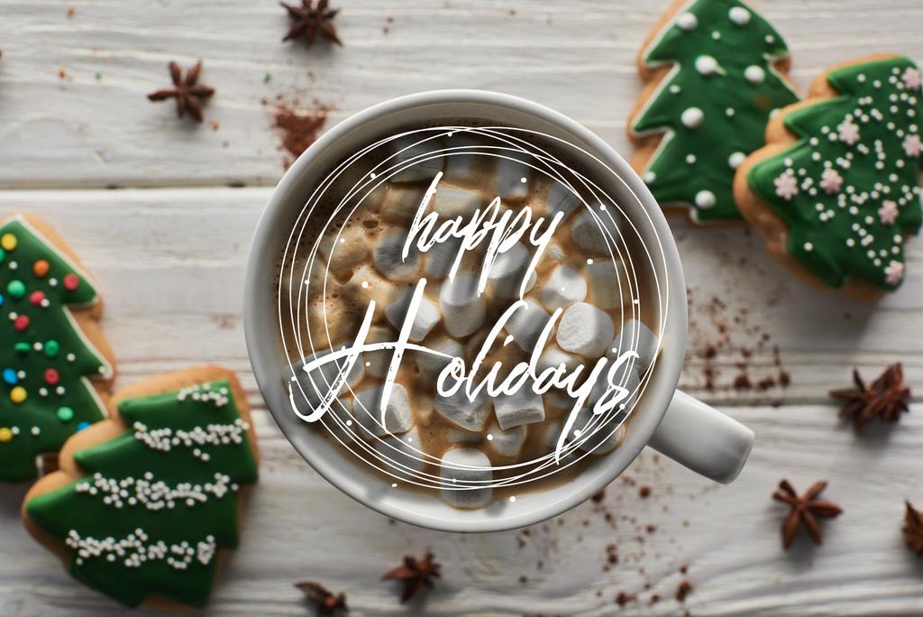 вид на рождественское какао с зефиром в кружке на белом деревянном столе рядом с анисом и печеньем с праздничной иллюстрацией
  - Фото, изображение