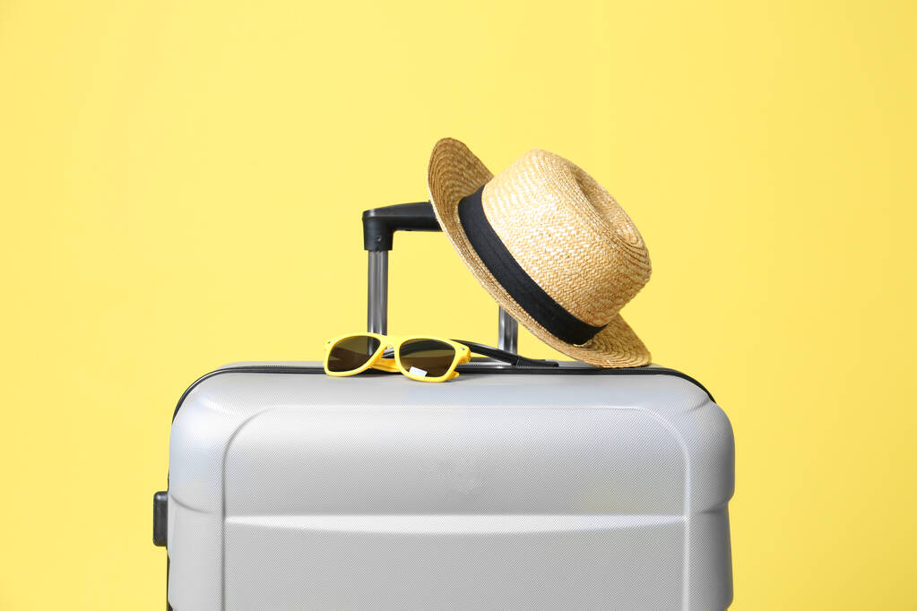 Güneş gözlüklü gri bavul ve sarı arka planda şapka - Fotoğraf, Görsel
