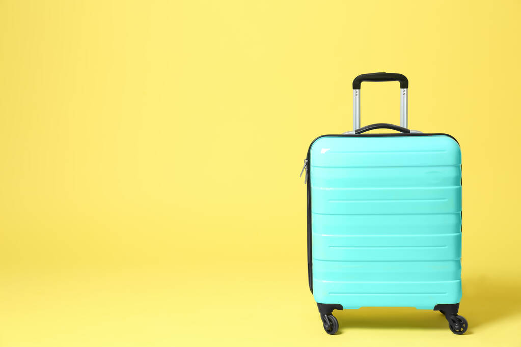 Stylowa turkusowa walizka na żółtym tle. Miejsce na tekst - Zdjęcie, obraz