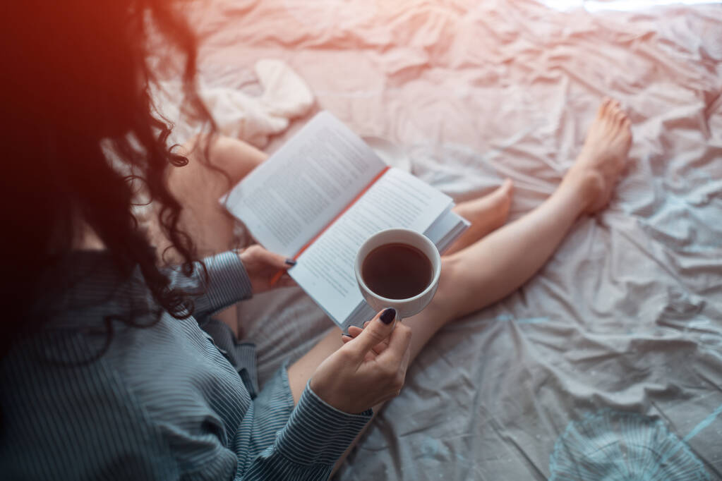 bonita mujer morena en la cama de la mañana con libros y café - Foto, Imagen