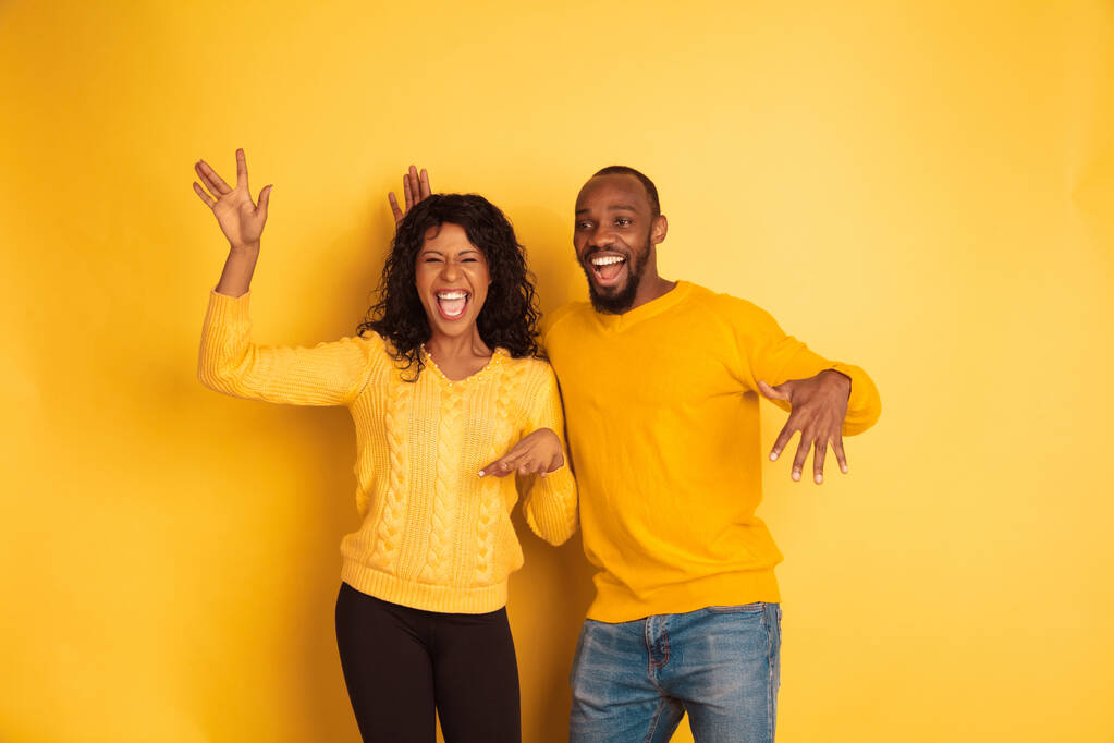 Mladý emocionální afroameričan muž a žena na žlutém pozadí - Fotografie, Obrázek