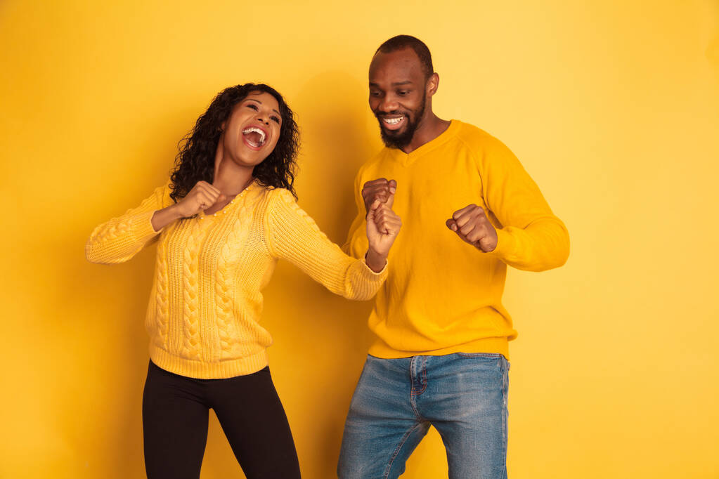 Jonge emotionele Afrikaans-Amerikaanse man en vrouw op gele achtergrond - Foto, afbeelding