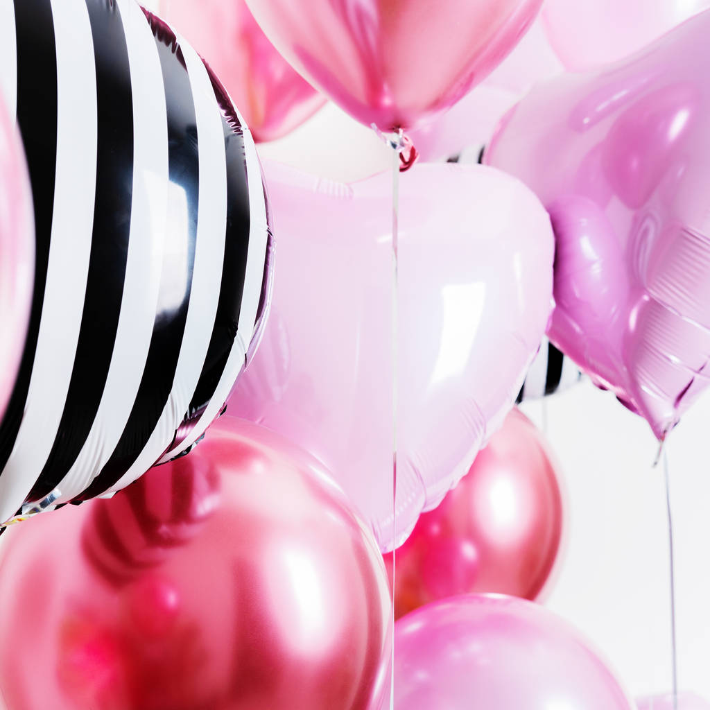 Set van ballonnen in de vorm van een hart en rond roze en gestreept op lichte achtergrond met kopieerruimte. - Foto, afbeelding