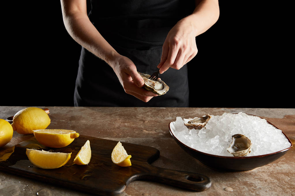 vue recadrée d'une femme tenant une fourche près d'une huître isolée sur fond noir
  - Photo, image