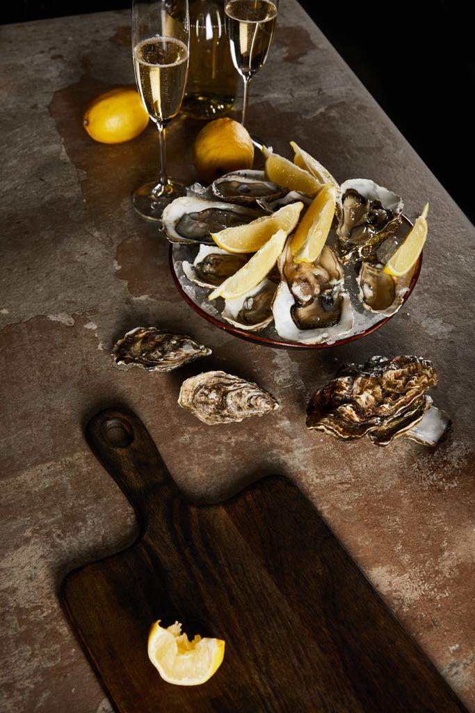 champagneglazen met mousserende wijn bij fles, oesters en citroenen in kom  - Foto, afbeelding