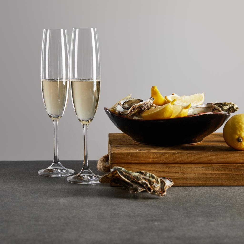 ostras frescas y limones en tazón cerca de copas de champán con vino espumoso aislado en gris
  - Foto, Imagen
