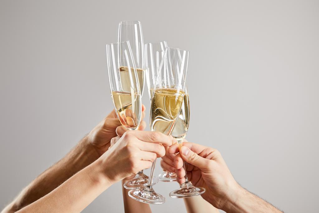 abgeschnittene Ansicht von Männern und Frauen, die Champagnergläser mit frischem Sekt isoliert auf Grau anstoßen  - Foto, Bild