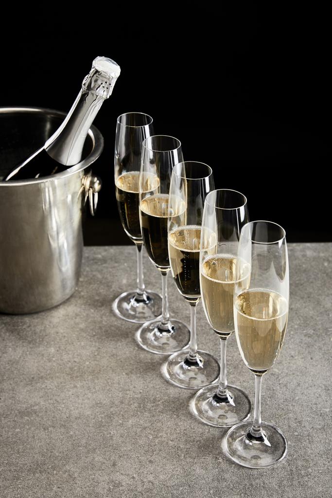 champagne glasses with sparkling wine near bottle in ice bucket isolated on black  - Photo, Image