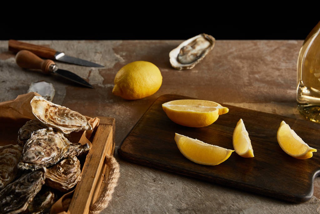 selective focus of delicious oysters in shells near lemons and knifes  - Photo, Image