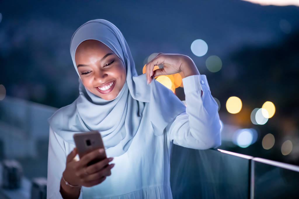 Gece sokakta telefon kullanan genç Müslüman kadın. - Fotoğraf, Görsel