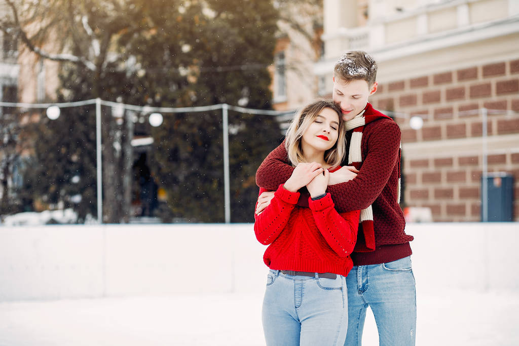 Roztomilý a milující pár v červených svetrech v zimním městě - Fotografie, Obrázek
