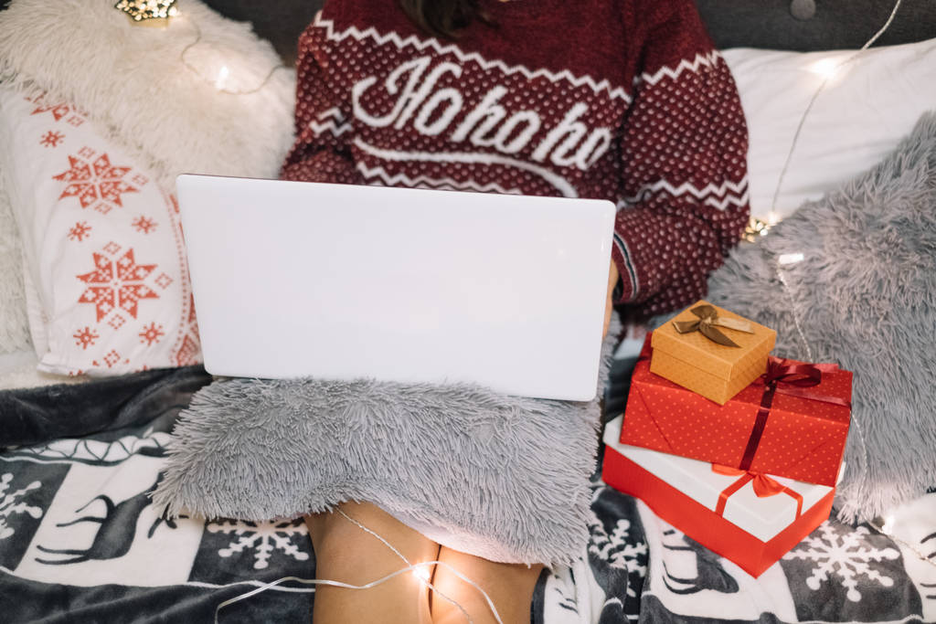 Κορίτσι με λευκό φορητό υπολογιστή στο κρεβάτι με φώτα Χριστουγέννων - Φωτογραφία, εικόνα