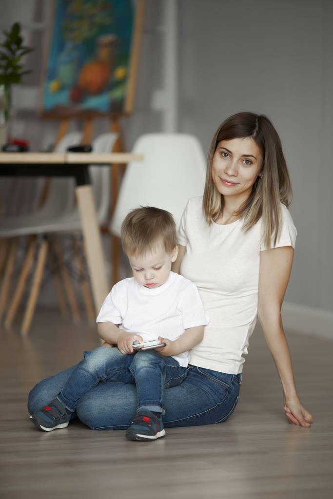 Woman and little son sitting on floor in apartment - 写真・画像